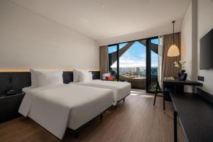 a bedroom with two beds and a desk and a window at Caro Premium Danang Hotel in Danang