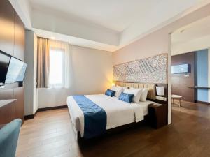 een hotelkamer met een bed en een flatscreen-tv bij @HOM Premiere Timoho in Yogyakarta