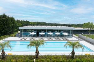 a building with a swimming pool and palm trees at Kylin Villa resort Jeju in Seogwipo