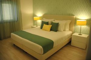 ein Schlafzimmer mit einem großen Bett mit grünen und gelben Kissen in der Unterkunft Hotel Dom Lourenco in Areia Branca