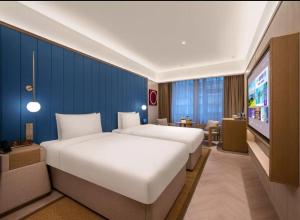 a hotel room with two beds and a tv at 北京奥体中心鸟巢桔子水晶酒店 in Beijing +10 photos