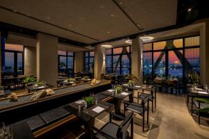 a restaurant with tables and chairs and windows at Caro Premium Danang Hotel in Danang