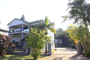 a white house with a gate and palm trees at Marionguesthouse in Ballito