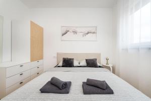 a white bedroom with a large bed with two pillows at Three Seas in Maslenica