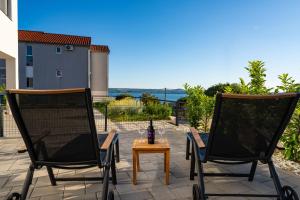 two chairs and a table with a bottle of wine on a patio at Three Seas in Maslenica