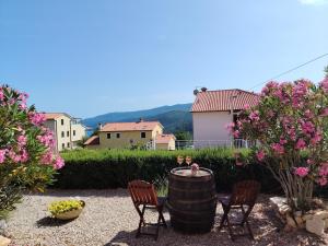 a patio with two chairs and a barrel and flowers at Del Mar Rabac in Rabac