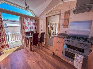 a kitchen with a stove and a table with chairs at Beautiful, Pet Friendly Caravan By The Beach In Suffolk Ref 40126Nd in Lowestoft