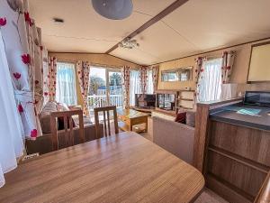een woonkamer met een tafel en een keuken bij Modern Caravan With Decking At Haven Hopton-On-Sea Ref 80032M in Great Yarmouth