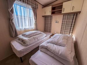 twee bedden in een kleine kamer met een raam bij Modern Caravan With Decking At Haven Hopton-On-Sea Ref 80032M in Great Yarmouth +13 foto's