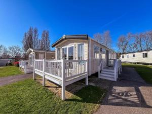 een klein huisje met een veranda en een witte balustrade bij Modern Caravan With Decking At Haven Hopton-On-Sea Ref 80032M in Great Yarmouth