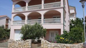 a large house with a balcony on top of it at Apartments Pink house in Povljana
