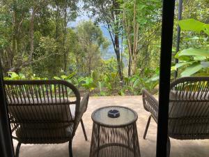 a patio with two chairs and a table with a bowl on it at Clovehigh Cabin and Homestay Munduk in Munduk +17 photos