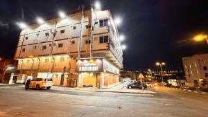 Un edificio con coches aparcados en un estacionamiento por la noche. en شقق ابراج الخير, en Abha