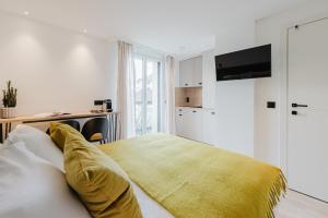 a bedroom with a bed with a yellow blanket on it at Appart Hotel Neostelia in Annecy