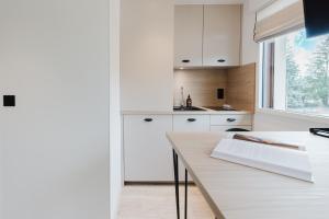 a kitchen with white cabinets and a wooden table at Appart Hotel Neostelia in Annecy