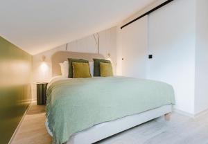 a bedroom with a large bed with green sheets and pillows at Appart Hotel Neostelia in Annecy