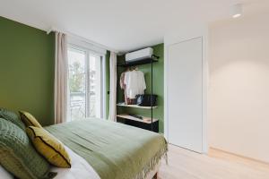 a green bedroom with a bed and a window at Appart Hotel Neostelia in Annecy