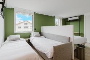 two beds in a room with green walls and a window at Appart Hotel Neostelia in Annecy