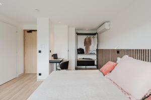 a bedroom with a white bed and a desk at Appart Hotel Neostelia in Annecy