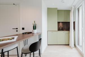 a kitchen with white cabinets and a counter and chairs at Appart Hotel Neostelia in Annecy