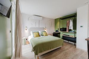 a bedroom with a bed with green sheets and a mirror at Appart Hotel Neostelia in Annecy