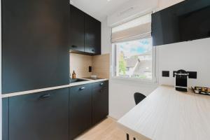 a kitchen with black cabinets and a white table at Appart Hotel Neostelia in Annecy +37 photos