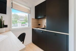 a kitchen with black cabinets and a table and a window at Appart Hotel Neostelia in Annecy