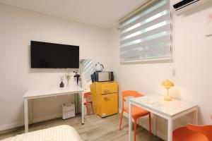 a living room with a desk and a tv on the wall at Hotel INSAENG Bucheon in Bucheon