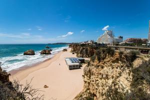 einen Strand mit Felsen, Meer und Gebäuden in der Unterkunft salgado`s nest in Portimão