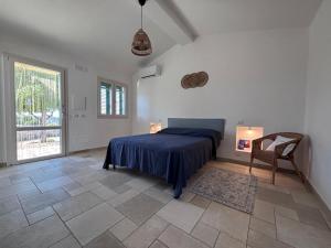 a bedroom with a bed and a chair and a window at La valle dei carrubi in Scicli