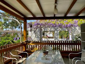 a table and chairs on a porch with purple flowers at 阿喜紫藤Arce wisteria in Meishan