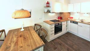 a kitchen with white cabinets and a wooden table at Haus Meeresblick - Ferienwohnung Stoertebeker A 0.17 (Ref. 138715 u1) in Baabe