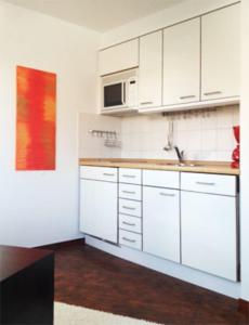 eine Küche mit weißen Schränken und einem Waschbecken in der Unterkunft Inselresidenz Strandburg - Ferienwohnung 305 (Ref. 50973) in Juist