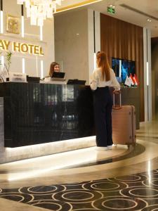 a woman standing in front of a hotel with a suitcase at Ankawa Holiday Hotel in Erbil