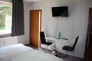 a hotel room with a bed and a desk and a television at Hotel Haus Hubertus in Schneverdingen