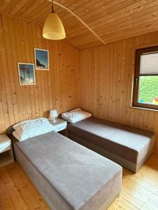 two beds in a room with wooden walls at Apartamenty na klifie in Debina