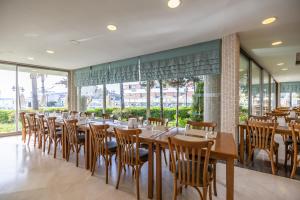 a restaurant with wooden tables and chairs and windows at Azure By Yelken Hotel in Turgutreis