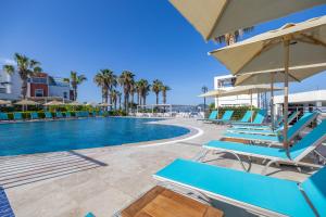 a swimming pool with blue chairs and umbrellas at Azure By Yelken Hotel in Turgutreis