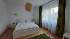 a bedroom with a white bed and a large window at Cosy House 400 m from Iulius Town in Timişoara