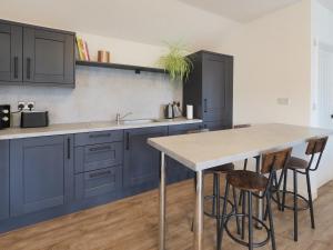 a kitchen with blue cabinets and a table with stools at Loxley's Lodge at Edwinstowe in Edwinstowe +3 photos