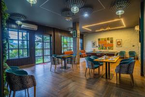 ein Restaurant mit Tischen und Stühlen und Fenstern in der Unterkunft Alaya Stays Sky Paradise Pet-friendly Retreat With Gaming Zone, Home Theatre & Rooftop Gazebo in Dehradun
