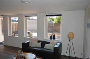 a living room with a couch and three windows at Beach Dream 3B in Petten