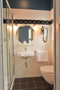 a bathroom with a sink and a toilet and a mirror at Hotel Le Rayon Vert in Étretat