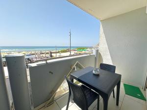 un tavolo e sedie su un balcone con vista sulla spiaggia di Le Grand Large - T2 vue océan a Mimizan-Plage