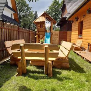 a wooden bench in a yard with a playground at Domek - Apartament Góralska Bajka, przy Krupówkach in Zakopane