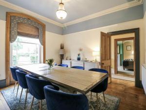 a dining room with a wooden table and blue chairs at Deeley House in Matlock