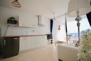a kitchen with white cabinets and a couch in a room at Marine Lovers - Jacuzzi Fuerteventura in Gran Tarajal