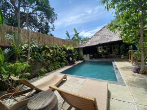 a swimming pool with chairs and a house at Casa Manalo Guest House in Puerto Princesa City
