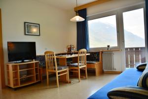 a living room with a table and chairs and a television at Residence Feldhof in Kastelbell-Tschars