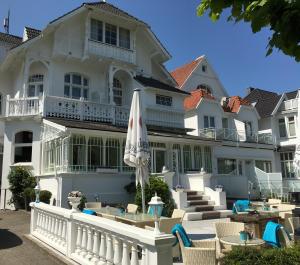 ein großes weißes Gebäude mit Stühlen und einem Sonnenschirm in der Unterkunft Villa WellenRausch - Adults Only in Travemünde